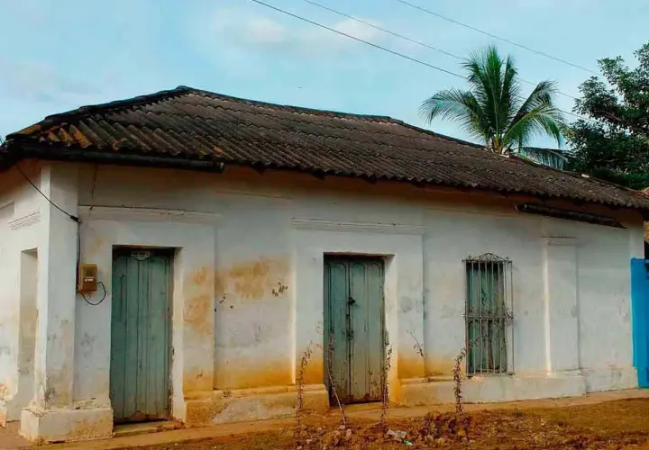 Casa antigua con tejas oscuras, dos puertas verdes y una ventana enrejada. El **precio** de esta **declaración de obra nueva antigua** es negociable.