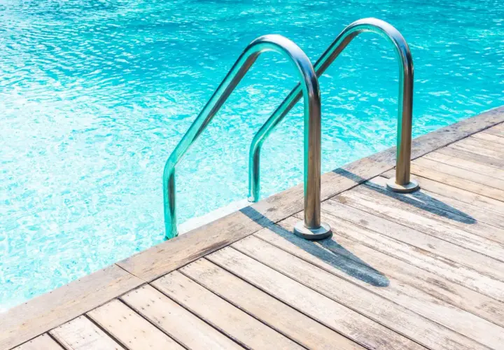Escaleras de piscina de acero inoxidable sobre cubierta de madera. ¿Cuánto cuesta hacer una piscina?