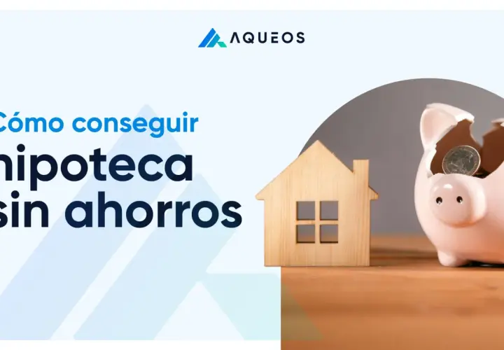 Cómo conseguir hipoteca sin ahorros. Una casa de madera y una hucha rota con monedas simbolizan el sueño de la vivienda.