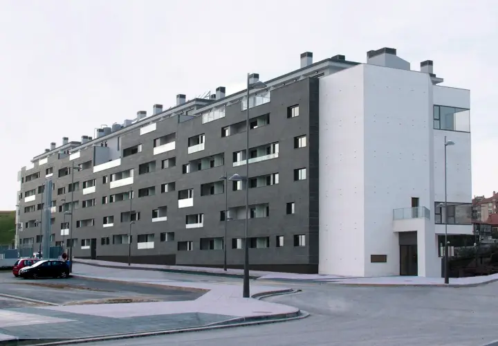 Edificio moderno con fachada de piedra oscura y blanca. ¿Buscas como saber si una vivienda es VPO? Este edificio podría serlo.