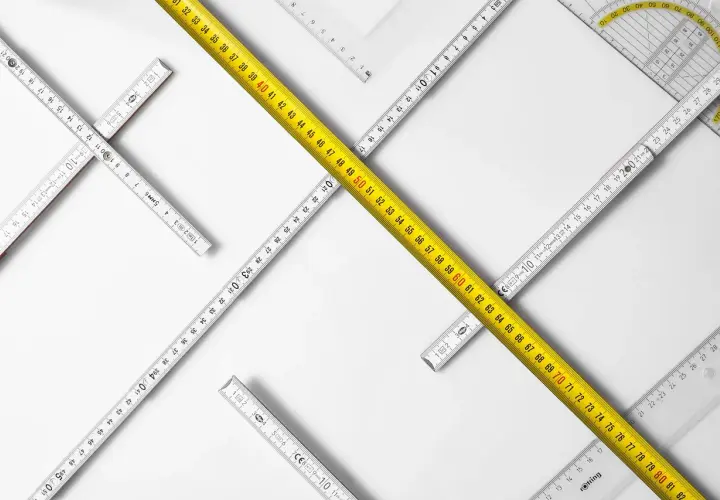Reglas de medición de diferentes tipos, incluyendo una cinta métrica amarilla, dispuestas en un patrón que sugiere la búsqueda de un cuerpo cierto.