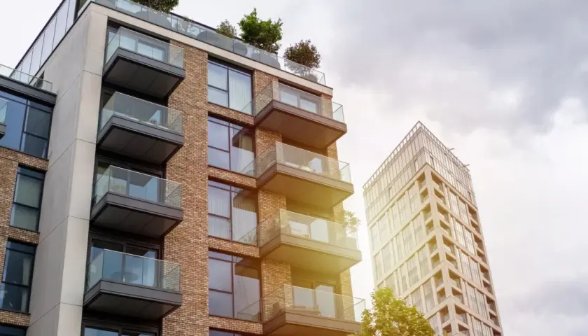Edificio moderno con balcones de cristal y ladrillo, parte de una parcela construida sin división horizontal.