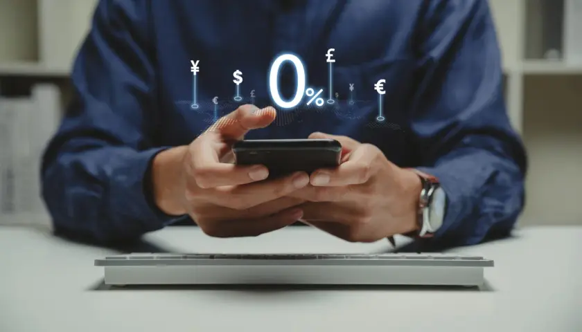 Man using smartphone with 0% interest and currency symbols, ideal for managing comisiones bancarias comunidades de propietarios.