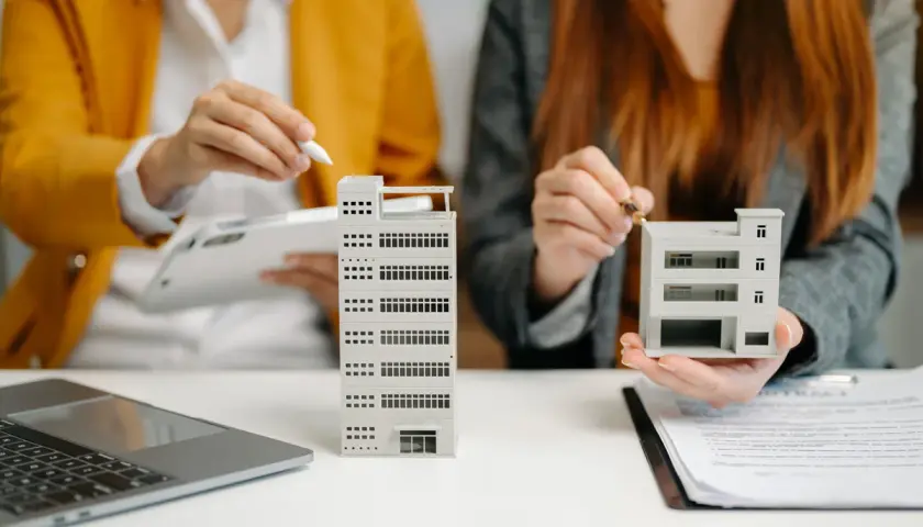 Dos personas analizan maquetas de edificios, como si estuvieran evaluando qué es un informe pericial inmobiliario.