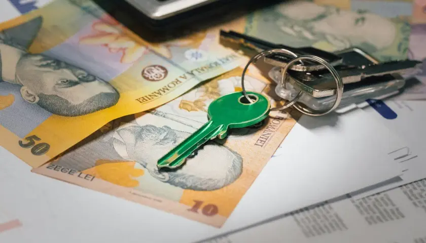 Llaves verdes y dinero rumano sobre documentos, sugiriendo un contrato de arras entre particulares para una compra.