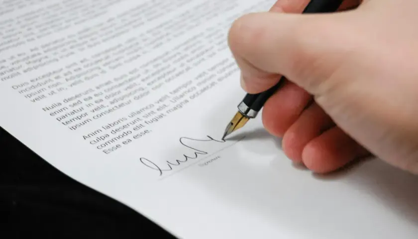 Firma de un certificado de deuda cero. La mano escribe con una pluma estilográfica sobre un documento legal.