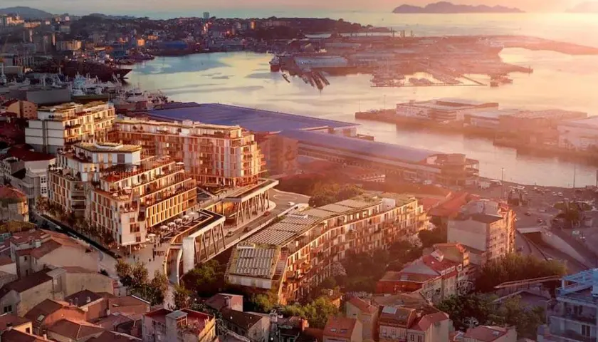 Vista aérea de un moderno complejo de edificios junto a un puerto, con islas al fondo. Un ejemplo de las mejores ciudades para vivir en España.