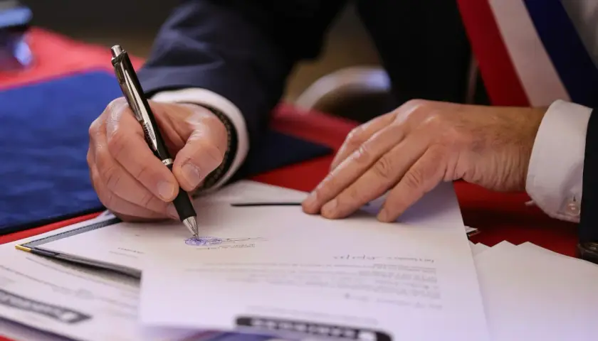 Mano firmando un documento oficial. El **valor pericial** de este acto es la validación de un acuerdo o testimonio.