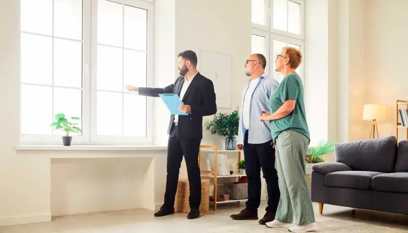 Agente inmobiliario muestra a una pareja una vivienda, explicando la **validez de la tasación de la vivienda** y sus características.