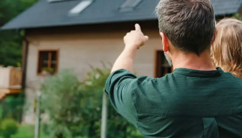 Padre e hija contemplan su futuro hogar. El padre señala el terreno, soñando con las hipotecas autopromotor que harán realidad su casa ideal.