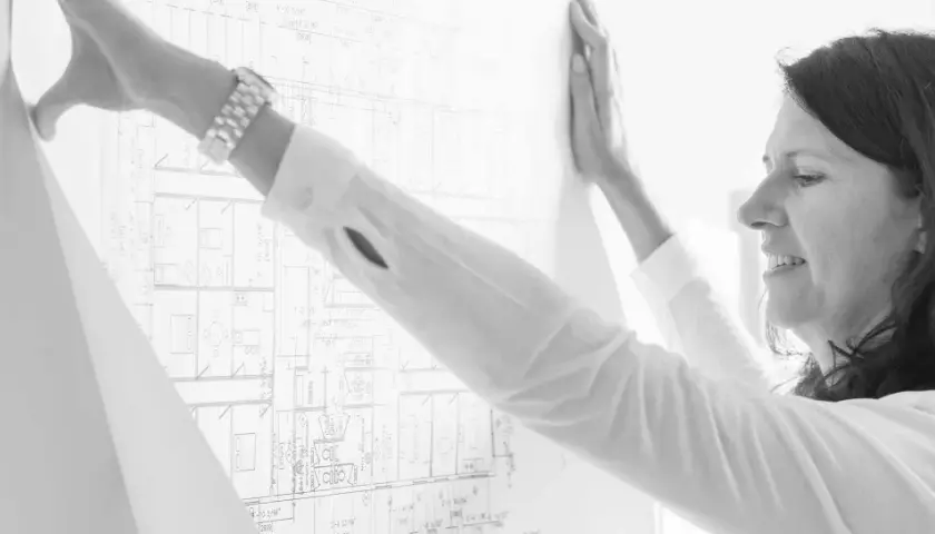 Mujer revisa un plano detallado, parte de un levantamiento de planos para un proyecto arquitectónico.
