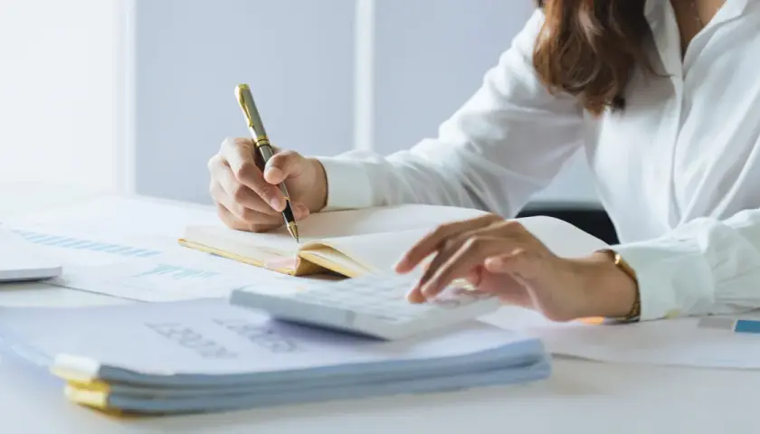 Persona revisa documentos y usa calculadora. Se prepara para declarar la nuda propiedad en la renta.