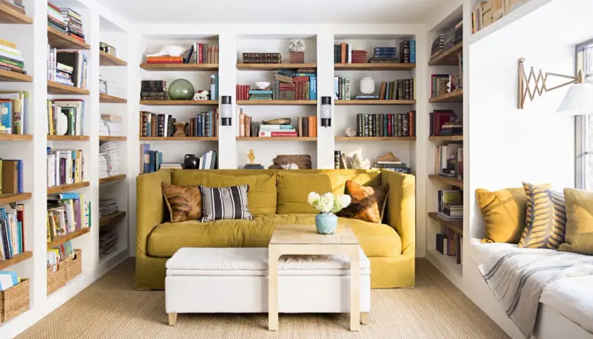 Sofá amarillo y estanterías llenas de libros, una **obra menor** de decoración acogedora.