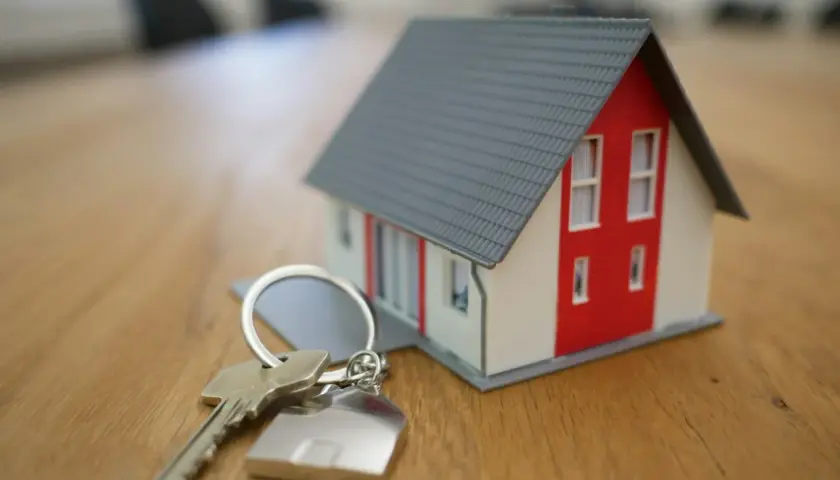 Llaves de una casa modelo sobre una mesa de madera, simbolizando la nueva ley de vivienda y la esperanza de un hogar.