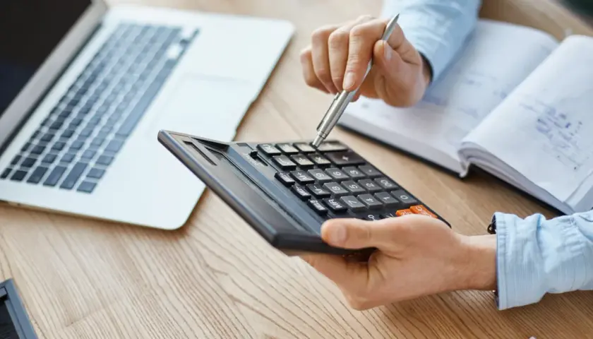 Persona calculando con calculadora y portátil, quizás para entender qué es el IBI.