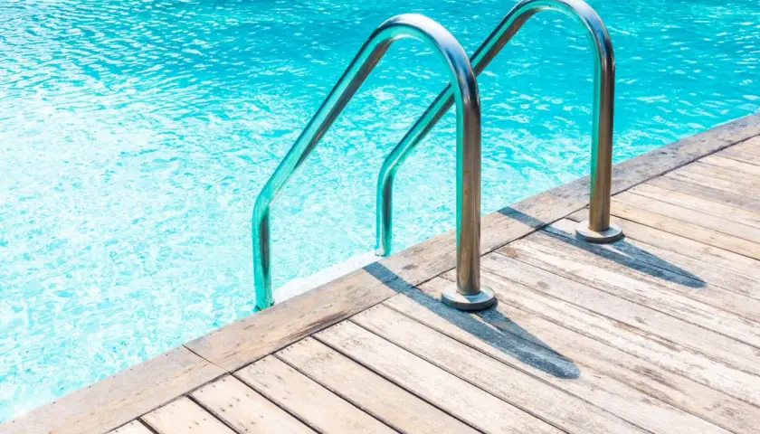 Escaleras de piscina de acero inoxidable sobre cubierta de madera. ¿Cuánto cuesta hacer una piscina?