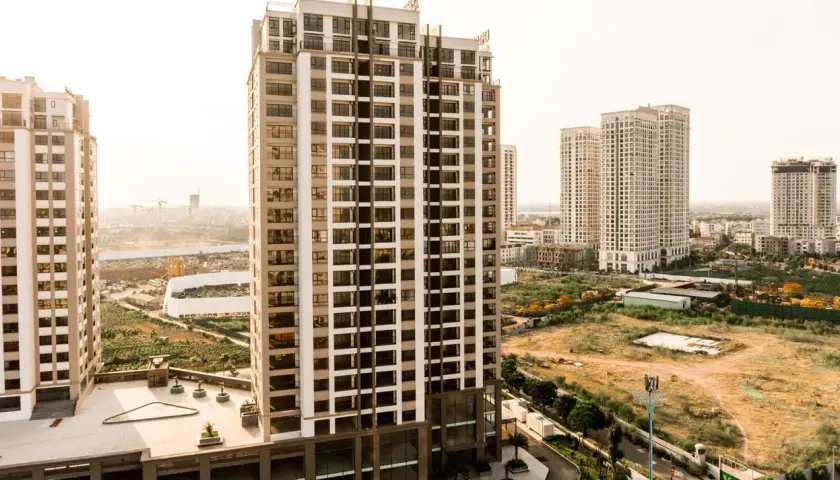 Edificios modernos se alzan sobre un **terreno urbano no consolidado**, con vegetación y construcciones en proceso.