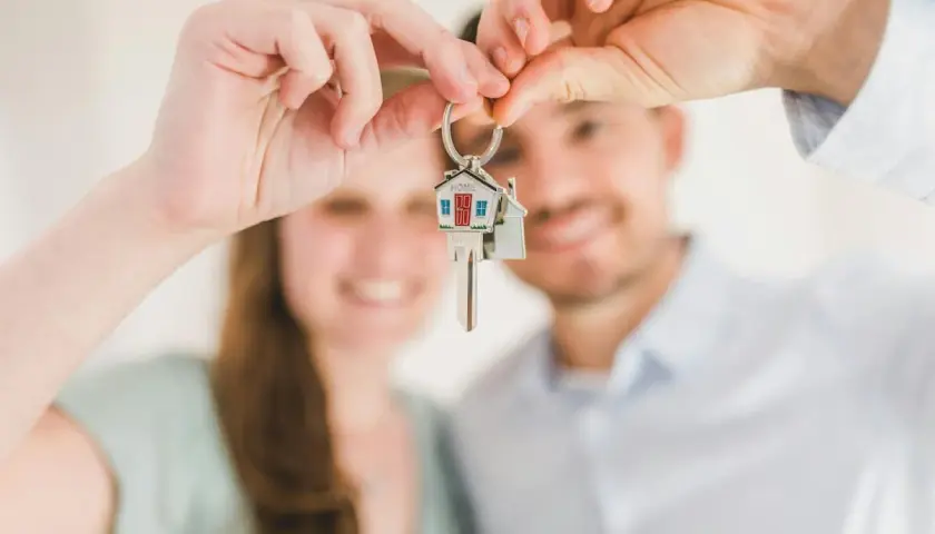 Pareja feliz sosteniendo llaves de casa. ¿Cuánto cobra Tecnocasa por vender un piso?