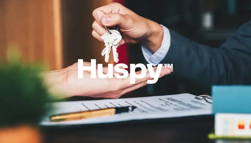Manos intercambiando llaves sobre un contrato. Las opiniones sobre Huspy son positivas, facilitando transacciones inmobiliarias.