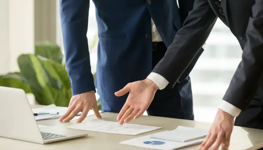 Dos hombres de negocios analizan un plano. Se discute el precio del informe pericial arquitecto.