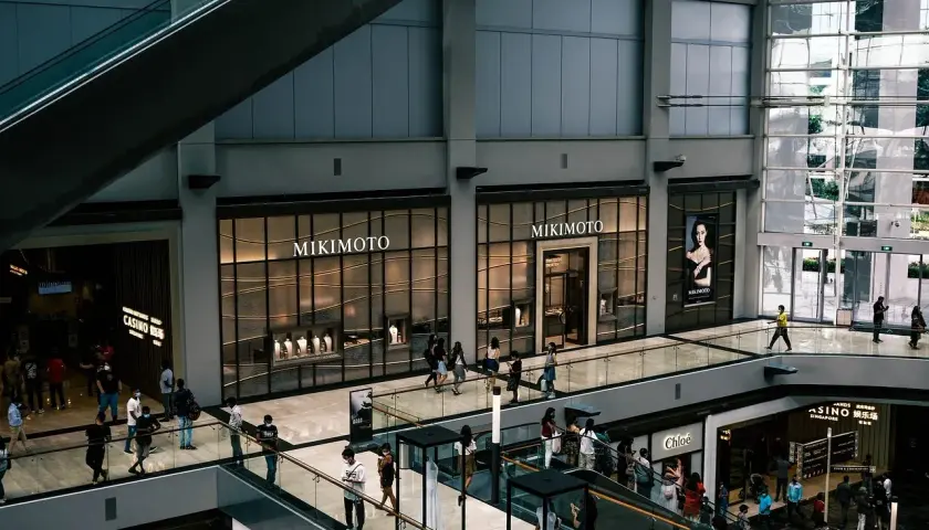 Interior de centro comercial con escaleras mecánicas y tiendas de lujo. La tasación de locales comerciales es clave para el valor de estos espacios.