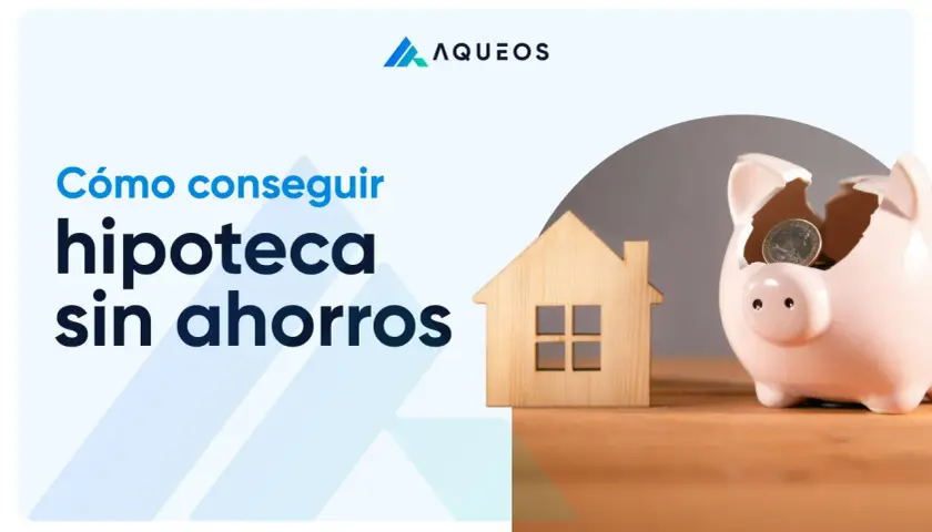 Cómo conseguir hipoteca sin ahorros. Una casa de madera y una hucha rota con monedas simbolizan el sueño de la vivienda.