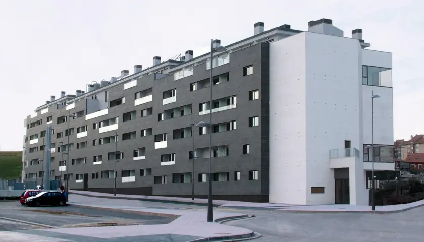 Edificio moderno con fachada de piedra oscura y blanca. ¿Buscas como saber si una vivienda es VPO? Este edificio podría serlo.