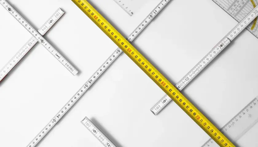 Reglas de medición de diferentes tipos, incluyendo una cinta métrica amarilla, dispuestas en un patrón que sugiere la búsqueda de un cuerpo cierto.