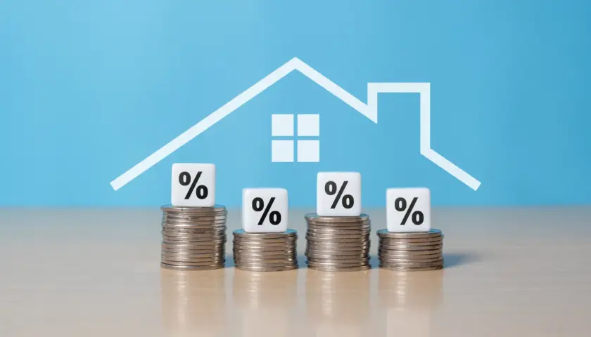 Montones de monedas con cubos de porcentaje y un contorno de casa. ¿Cuánto hay que tener ahorrado para comprar un piso?