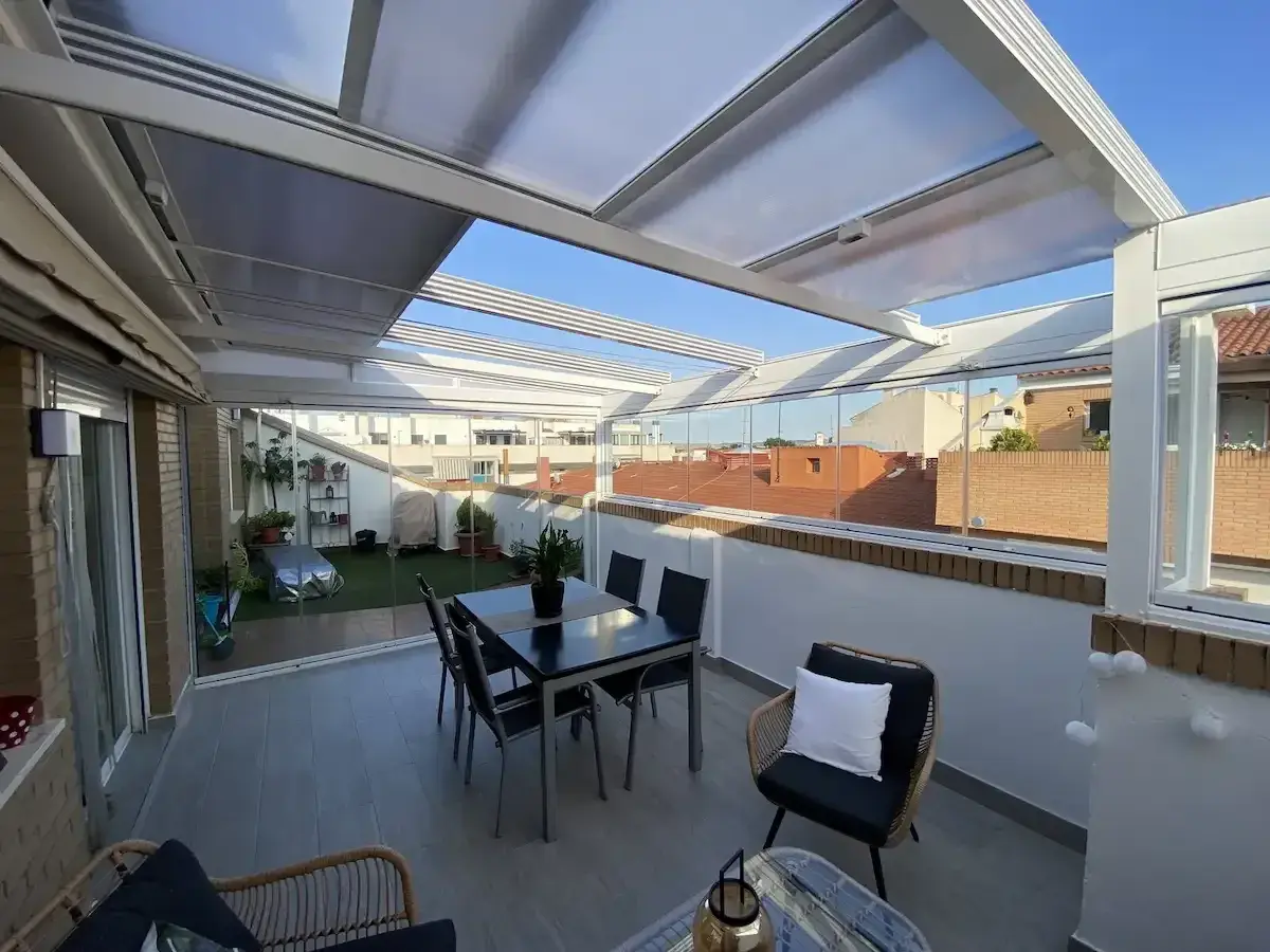 Cerramiento terraza casa unifamiliar con mesa y sillas, y zona ajardinada. Disfruta del exterior todo el año.