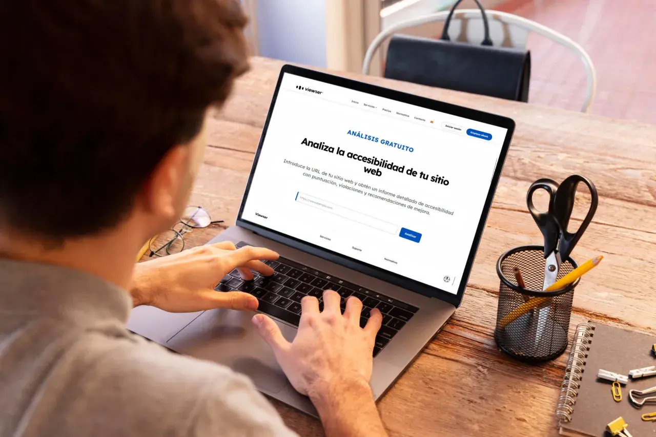 Persona usando laptop para obtener un informe de accesibilidad web. La pantalla muestra "Analiza la accesibilidad de tu sitio web".