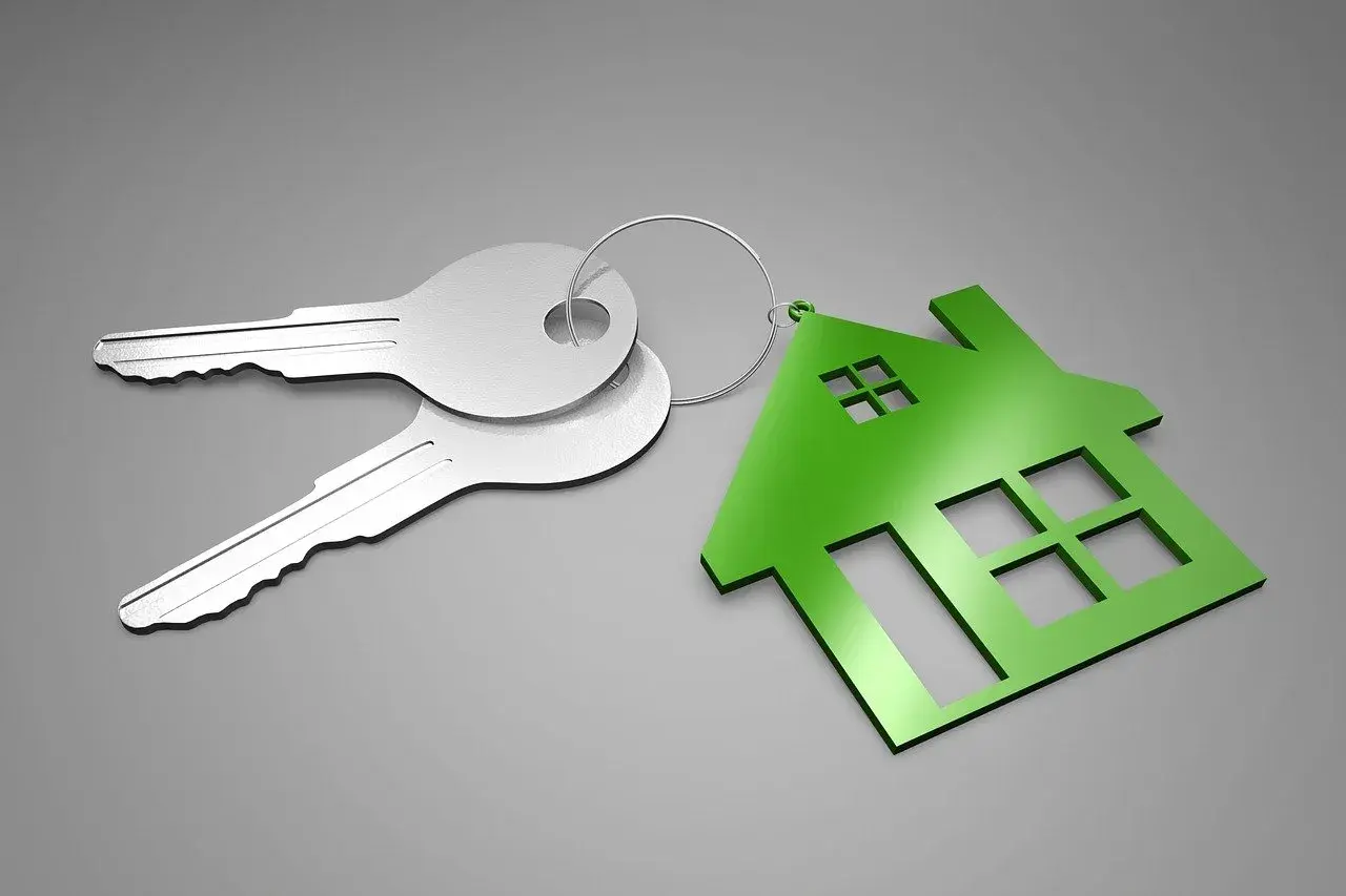 Dos llaves plateadas y un llavero con forma de casa verde. ¿Qué es el aval ico? Es la llave de tu nuevo hogar.