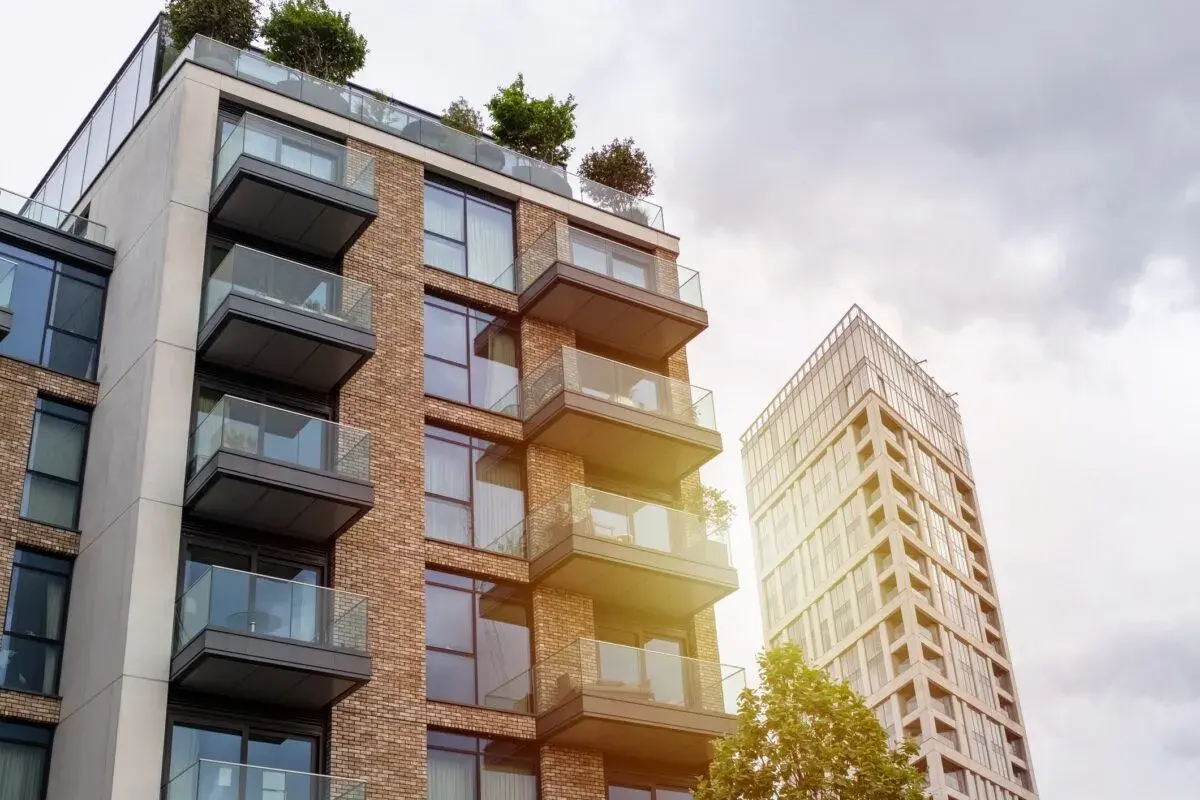 Edificio moderno con balcones de cristal y ladrillo, parte de una parcela construida sin división horizontal.