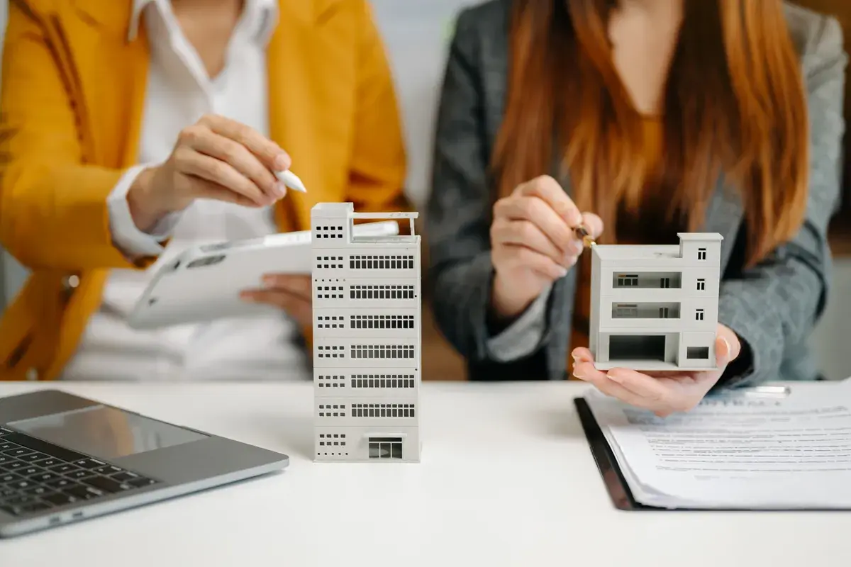 Dos personas analizan maquetas de edificios, como si estuvieran evaluando qué es un informe pericial inmobiliario.