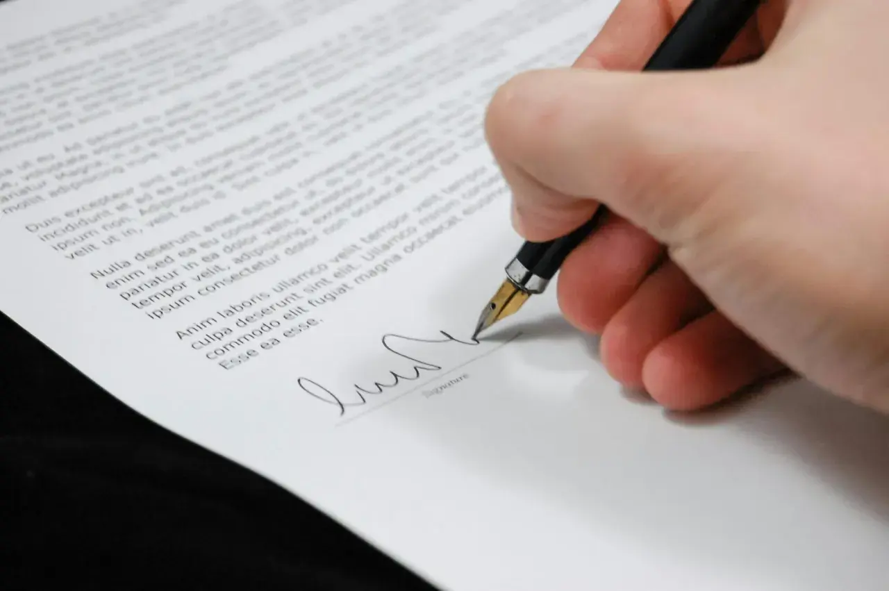Firma de un certificado de deuda cero. La mano escribe con una pluma estilográfica sobre un documento legal.