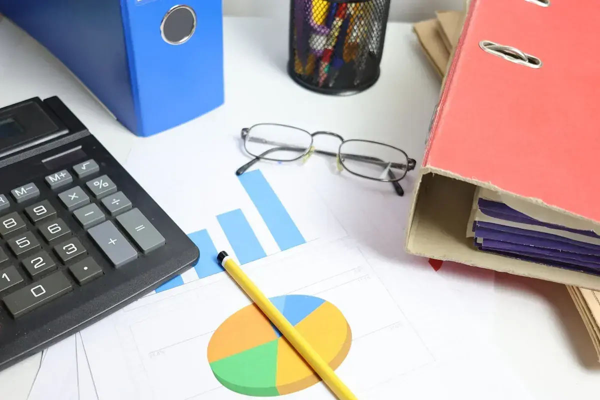 Calculadora, gráficos y carpetas sobre un escritorio. Analizando el tipo de interés actual para tomar decisiones financieras.