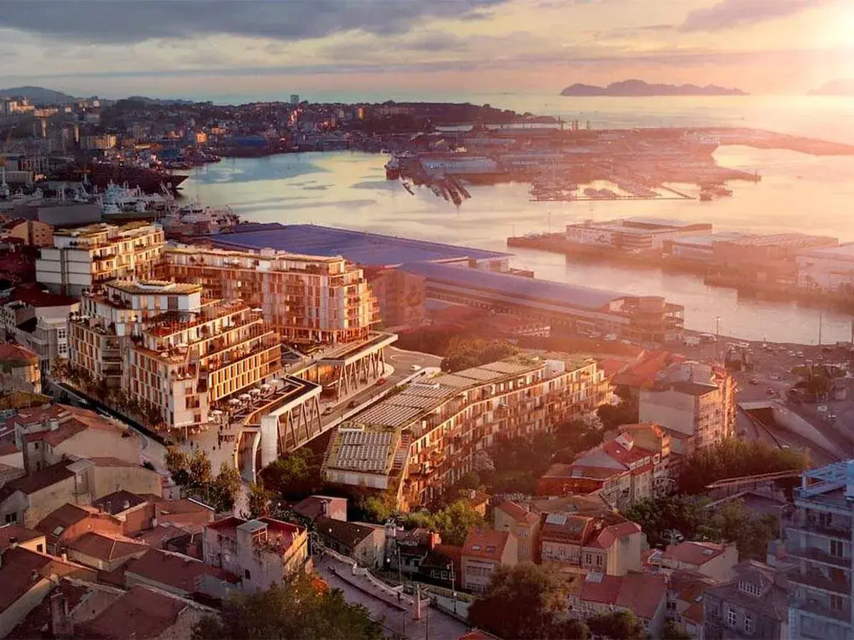 Vista aérea de un moderno complejo de edificios junto a un puerto, con islas al fondo. Un ejemplo de las mejores ciudades para vivir en España.