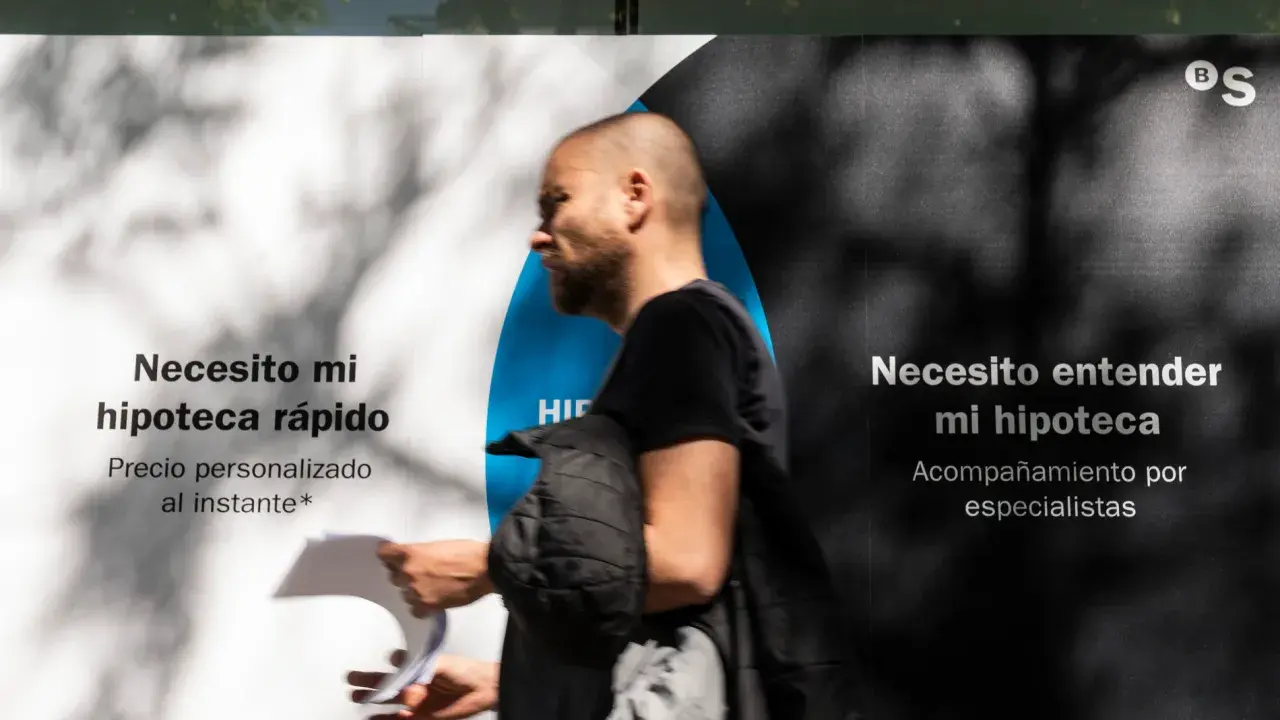 Hombre pasa frente a un anuncio que dice "Necesito mi hipoteca rápido" y "Necesito entender mi hipoteca". Pregunta: ¿quién paga el levantamiento de hipoteca?
