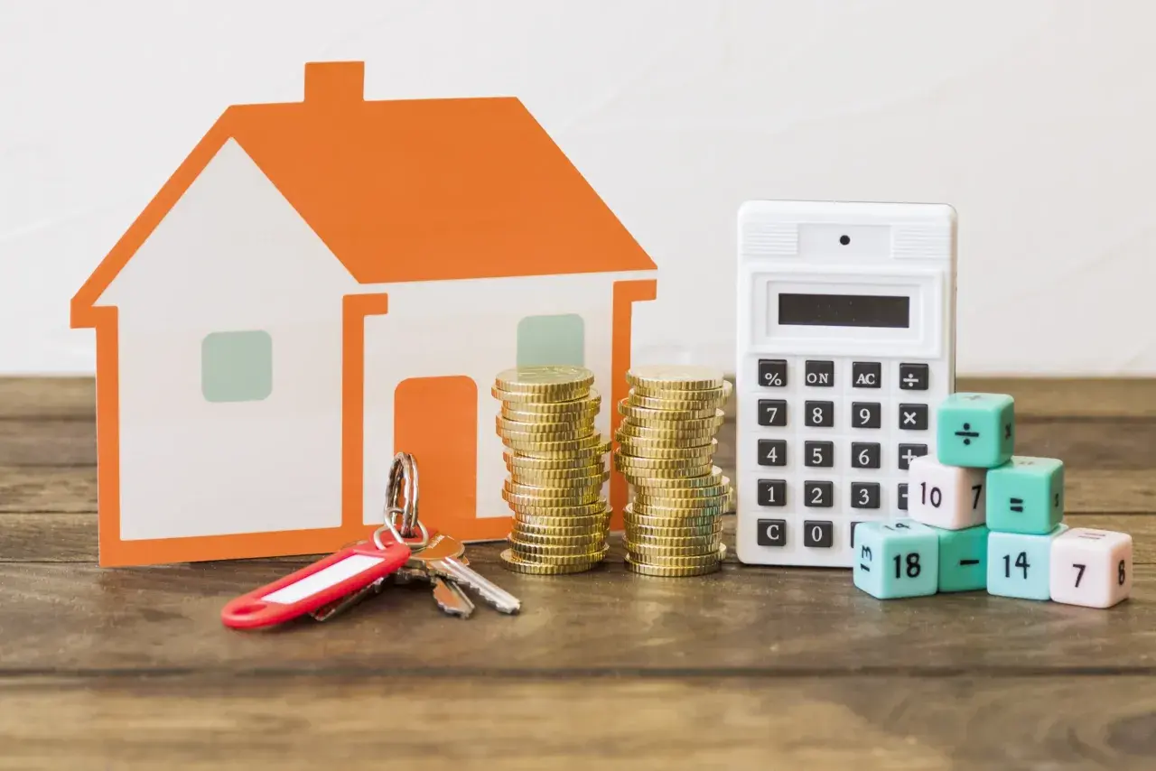 Casa naranja, llaves, monedas y calculadora. Los dados con números y símbolos matemáticos ilustran los gastos a la hora de comprar un piso.