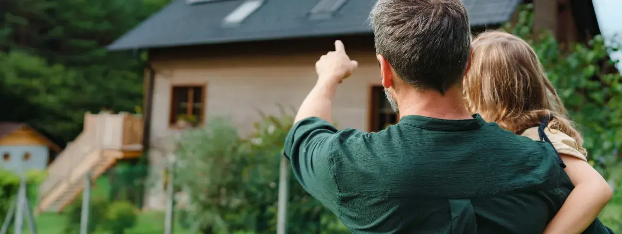 Padre e hija contemplan su futuro hogar. El padre señala el terreno, soñando con las hipotecas autopromotor que harán realidad su casa ideal.