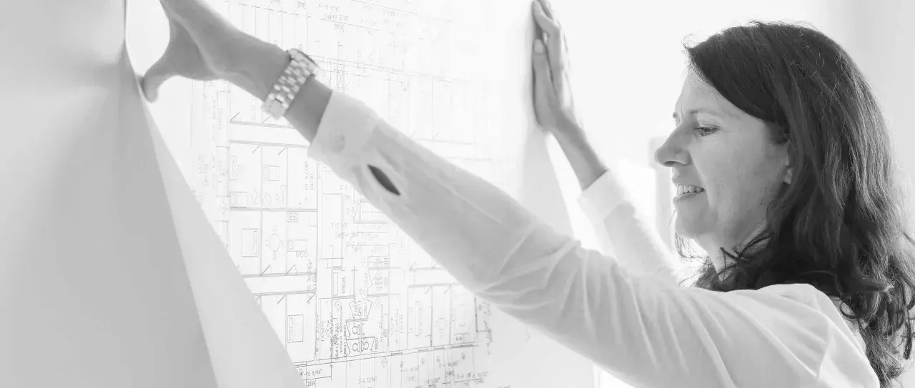 Mujer revisa un plano detallado, parte de un levantamiento de planos para un proyecto arquitectónico.