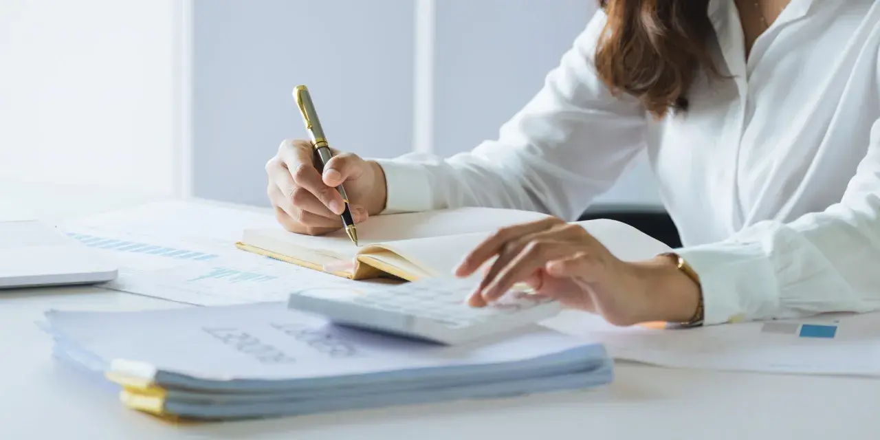 Persona revisa documentos y usa calculadora. Se prepara para declarar la nuda propiedad en la renta.
