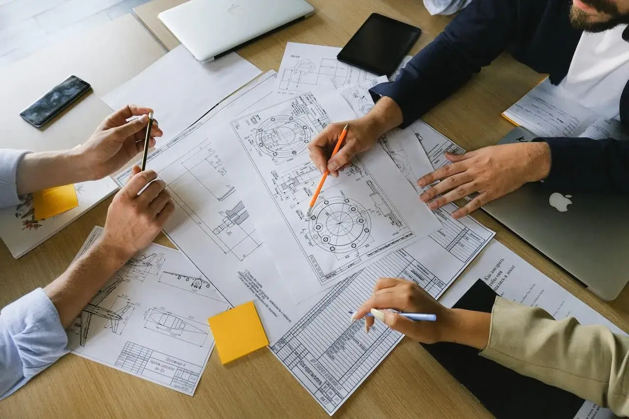 Manos revisando planos técnicos, un **informe pericial vivienda** en proceso.