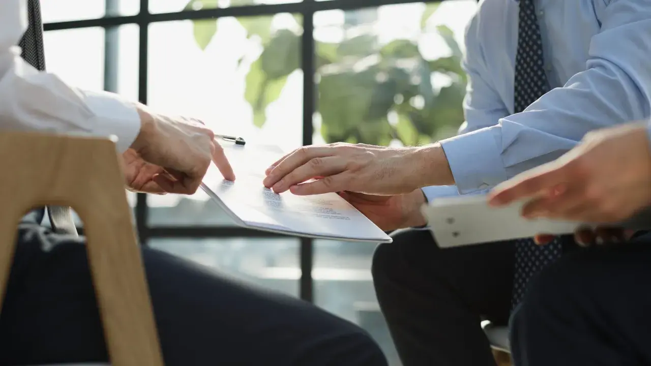 Manos revisando un documento, discutiendo cómo pedir nota simple.