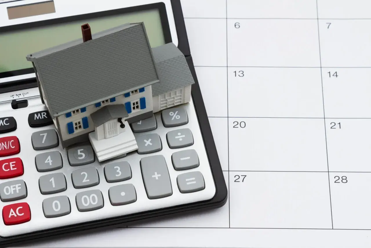 Casa en calculadora y calendario. Planifica tu hipoteca sin aval, calculando cada paso.
