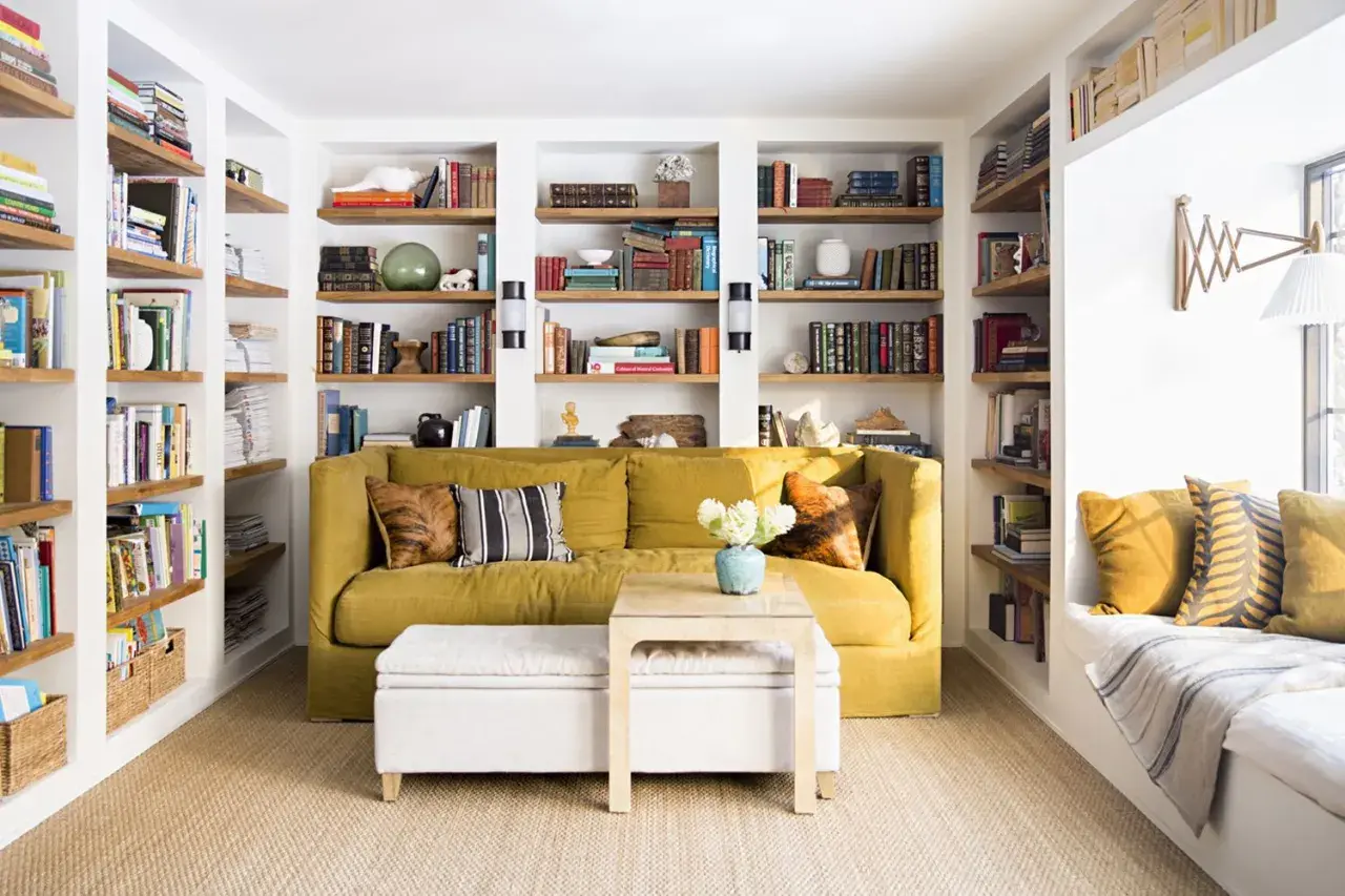 Sofá amarillo y estanterías llenas de libros, una **obra menor** de decoración acogedora.