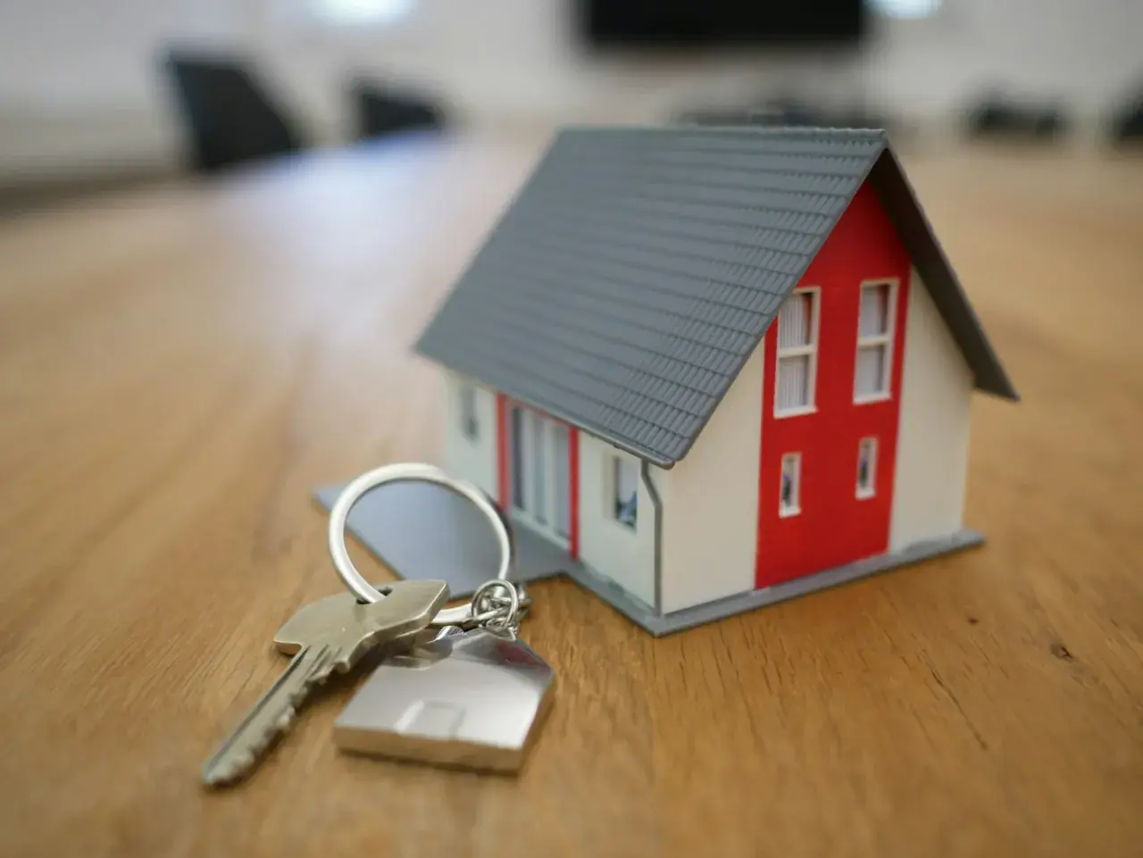 Llaves de una casa modelo sobre una mesa de madera, simbolizando la nueva ley de vivienda y la esperanza de un hogar.