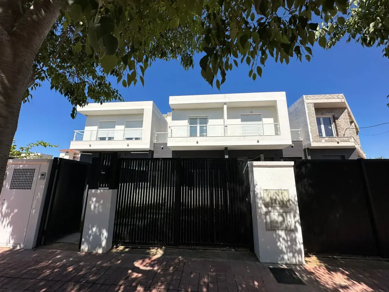 Modern houses behind a black gate. A tasador hipoteca would appreciate the clean lines and potential value.