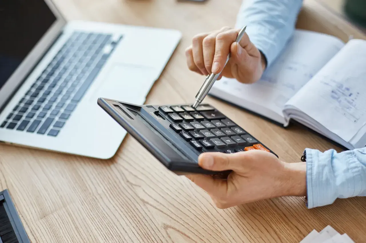 Persona calculando con calculadora y portátil, quizás para entender qué es el IBI.
