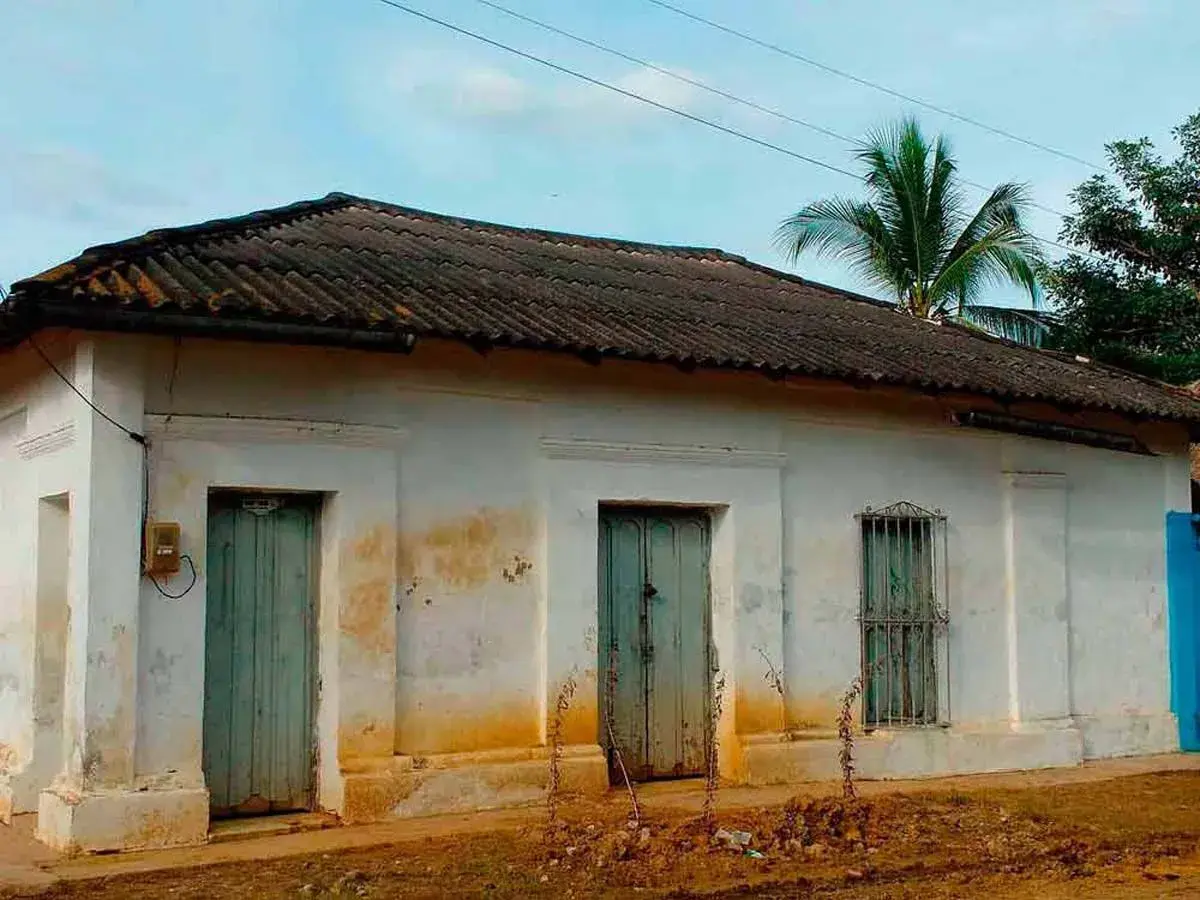 Casa antigua con tejas oscuras, dos puertas verdes y una ventana enrejada. El **precio** de esta **declaración de obra nueva antigua** es negociable.